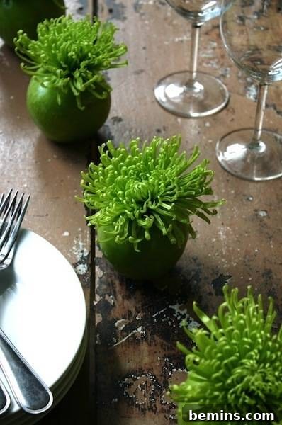 Four bright green plants in for bright green round planters on a table with place settings
