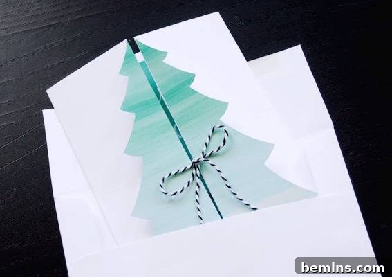DIY Christmas Tree Card Tutorial Free Template 9 A Christmas tree in the center of a card that is folded in half and closed in the center with a festive ribbon, showcasing the finished product.