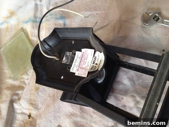 A black light fixture laying on its back with a black and white wire hanging out. Shows the disassembly process.