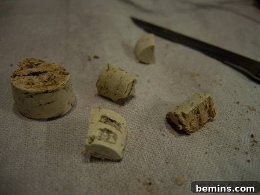 Cut up cork near metal knife on top of a canvas tarp. Cork pieces used for the feet.