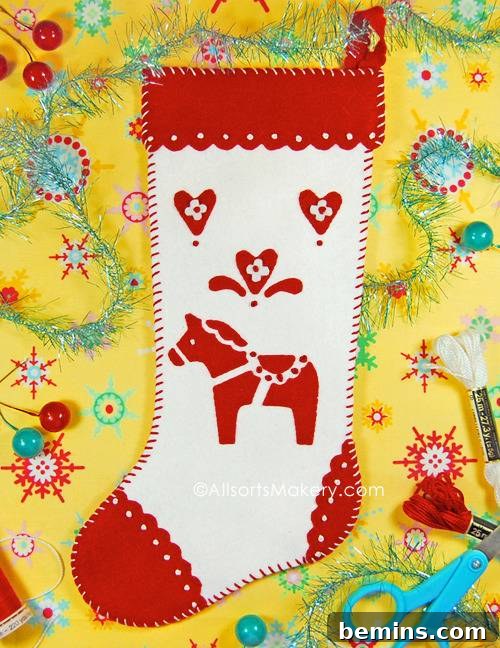 A red and white stocking featuring a traditional Swedish Dala Horse design, displayed on a yellow background with crafting tools, showcasing a touch of Scandinavian charm.