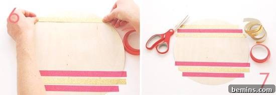 A person spreads pink tape over a wooden disk.