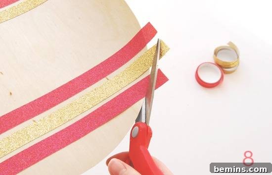 A person using scissors to cut away long edges of ribbon that have been glued to a circle.