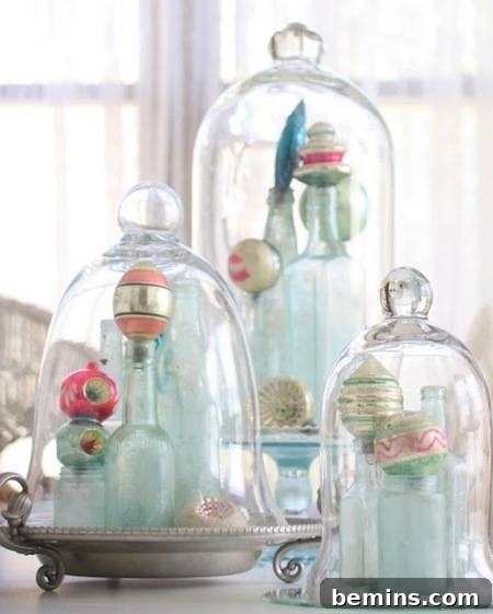 Antique glass ornaments displayed under bell jars, creating a vintage Christmas decoration.