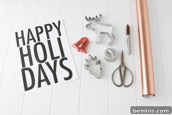 Craft Your Own Festive Wall Decor: Removable Decal Magic 3 A roll of copper wrapping paper sits next to scissors and cookie cutters next to a homemade card for happy holidays. DIY holiday crafting supplies.