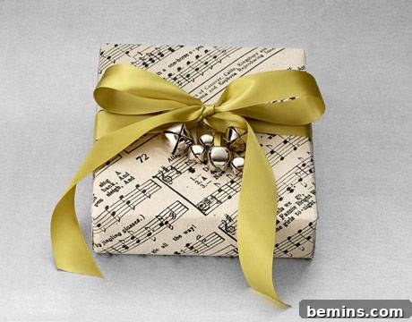 A present has been wrapped in sheet music and tied with a gold ribbon that has jingle bells attached to it.