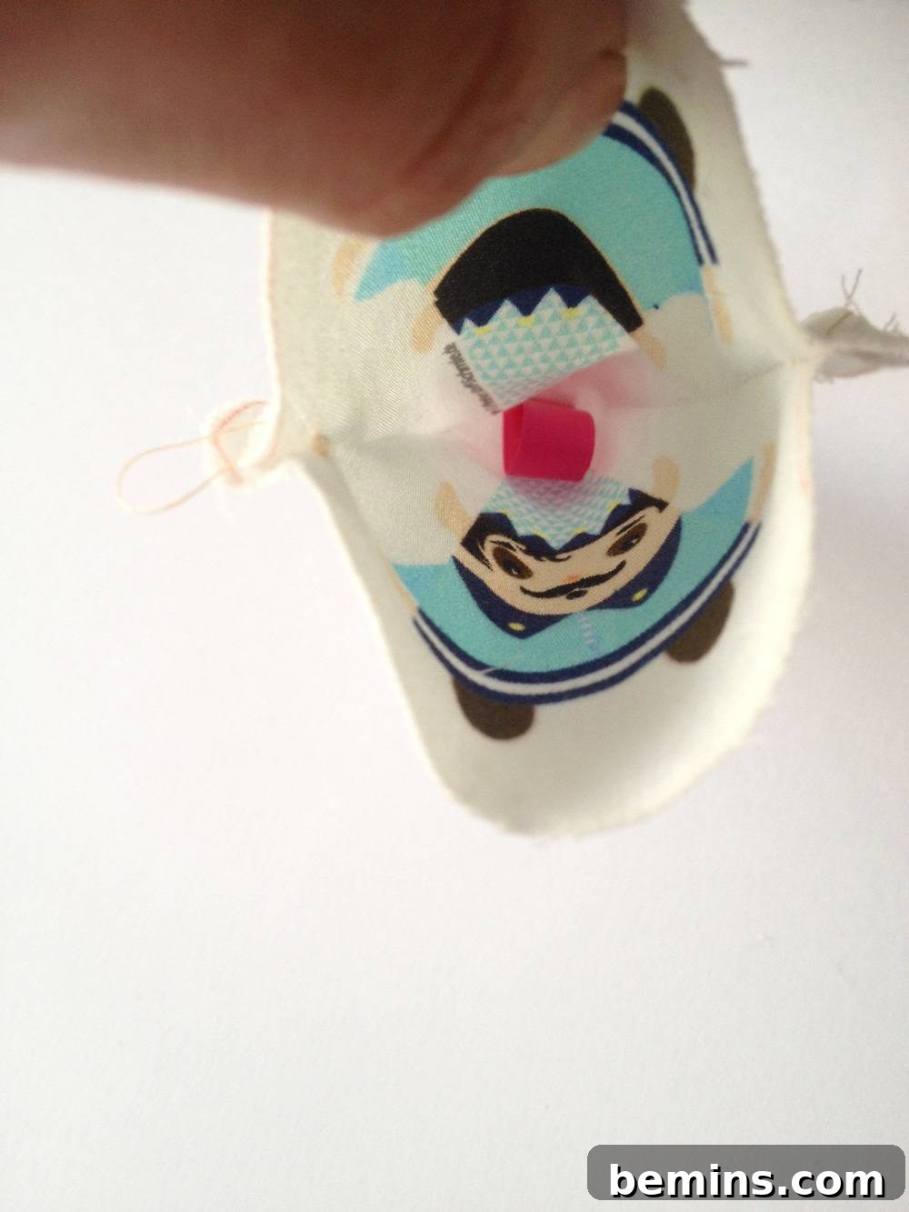 Hands holding the two layers of fabric with the ribbon loop in place
