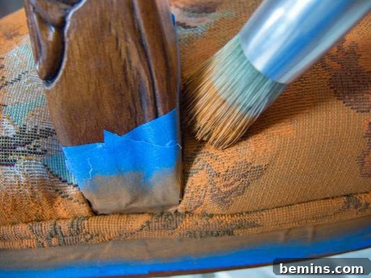 Close-up of a paint brush applying Annie Sloan chalk paint to the chair cushion.