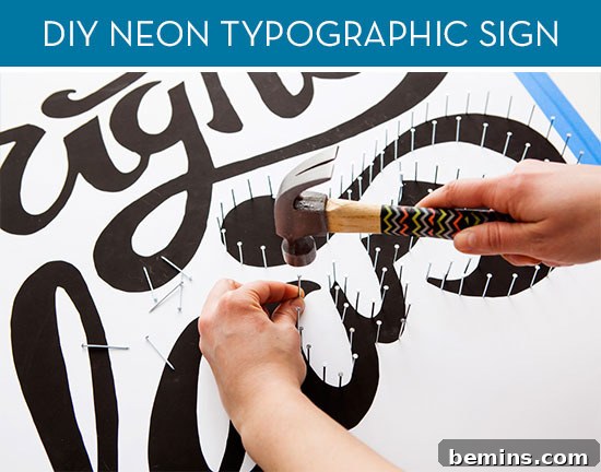 How to Craft a Glowing Typographic Display 2 A person uses a hammer to tap small nails into a sign going around the lettering