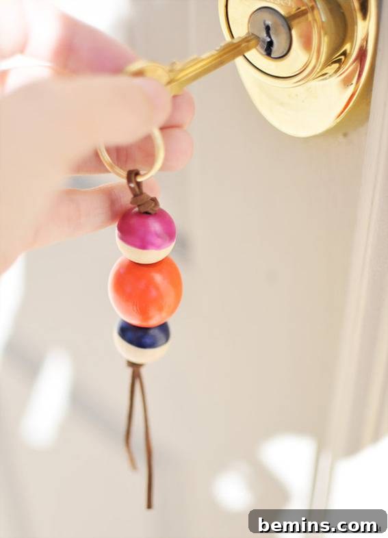 A person inserting a key into a door using a beaded keychain