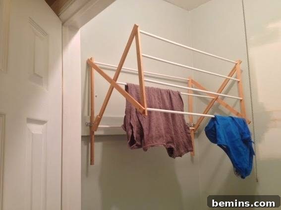A drying rack mounted in a closet, with clothing drying on it.