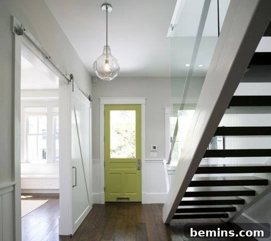 House interior with staircase, wooden floor, and a green main door