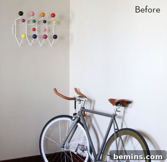 A white wall has hanging decor and a bike in front of it.