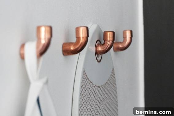 Four golden hangers against a textured white wall.