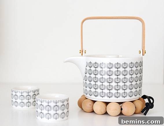 A pattern design tea kettle is next to two pattern design tea mugs.