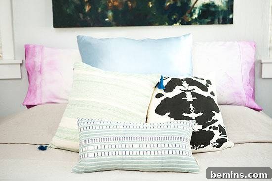 Dip-Dye Pillowcase Perfection: Achieving the Ombre Look with Ease 5 Pillows are sitting on a bed with a picture hanging over it.
