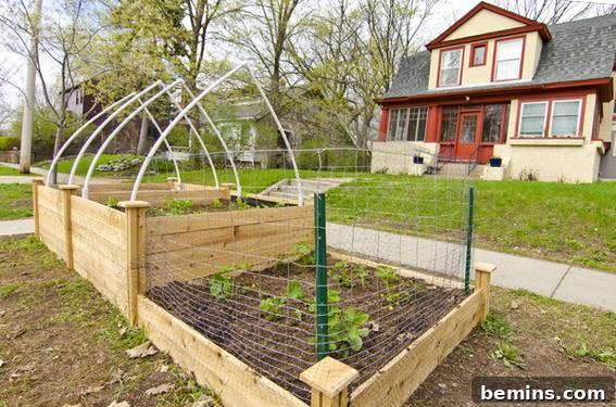 Raised Bed Revolution: Square Foot Gardening on a Grand Scale 13 An outdoor box gardent with a white frame over the top in front of a two story house with an orange front door.