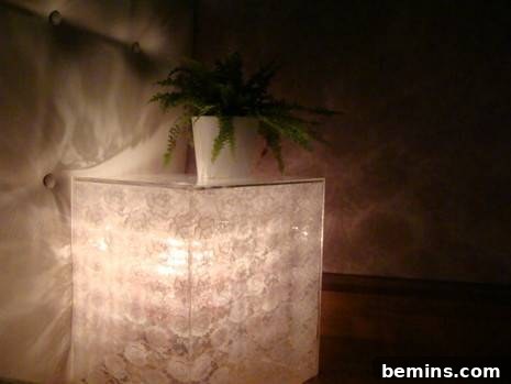 A plant is sitting on a lighted table.