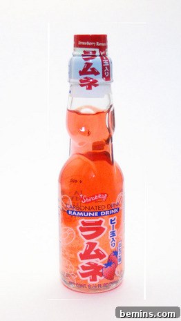A drink with orange liquid in a clear glass bottle, photographed in a DIY light box.
