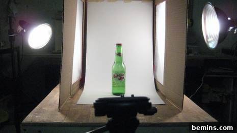 A green bottle inside a DIY light box ready for photography.