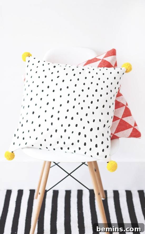 Updated cushion with paint and yarn pom-poms, adding a playful and textured element to your decor.