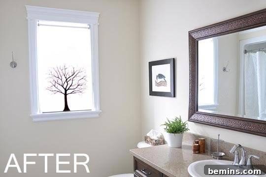 A tree image is on a frosted glass window in a bright white modem bathroom.