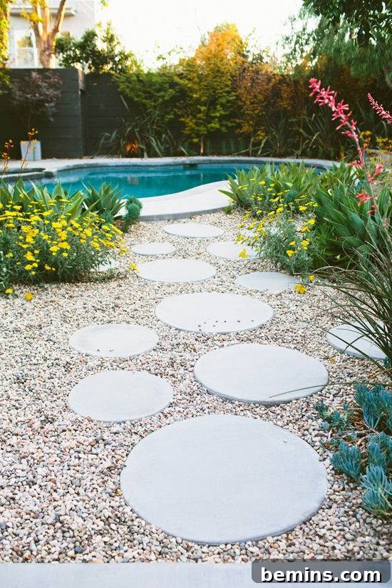 A backyard with a round step path set in gravel leading the way to an inground pool.