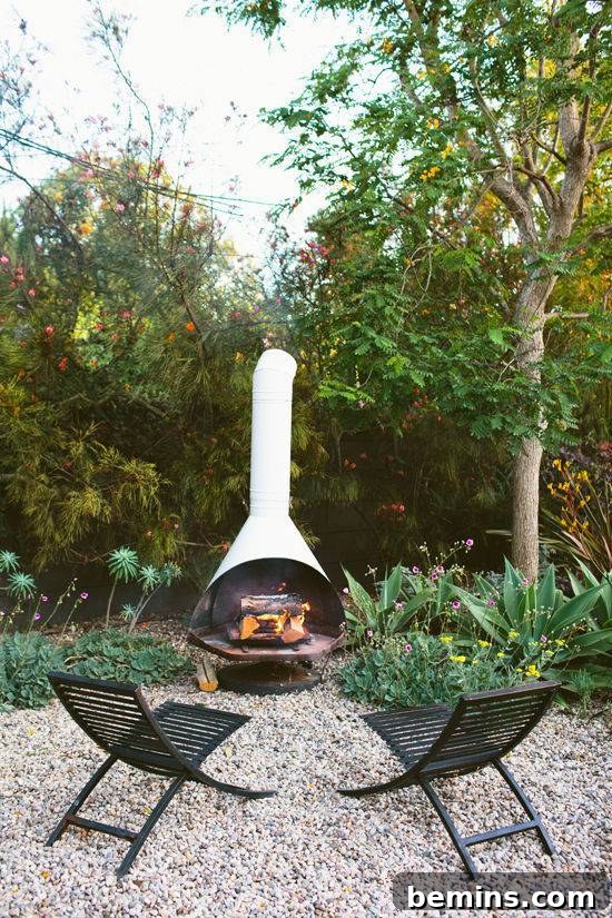 Two black chairs online near the fireplace in an open area surrounded by greenery.