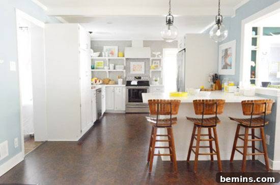 A bright white kitchen with a dining area, adorned with stylish wall frames, creating a clean, modern, and inviting atmosphere.