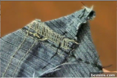 Close-up of a hand sewing a seam on denim fabric, creating the base of the jean purse.