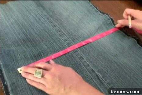 Measuring denim fabric with a tape measure to create the flap for the DIY jean purse.