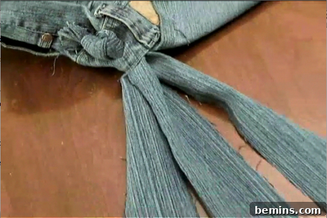 Braiding denim fabric strips to create a strap for the homemade jean purse.