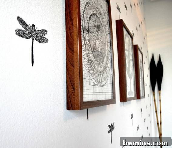 A dragonfly and other artwork hangs on a white wall.