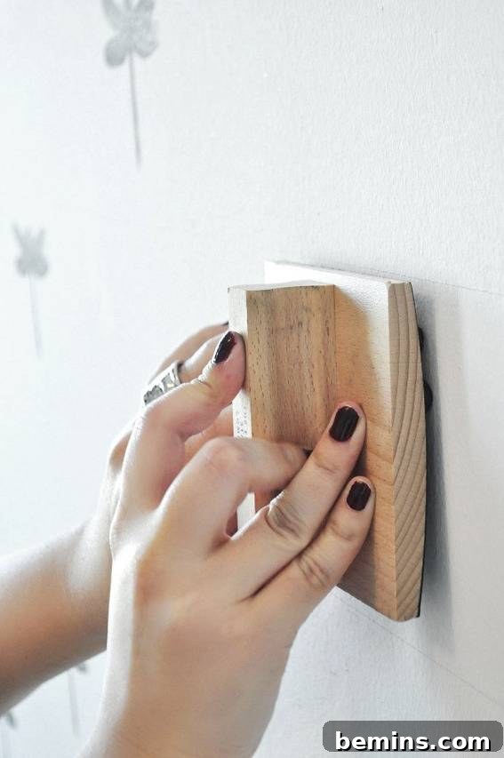 A person uses a wooden stamp to pattern a wall.