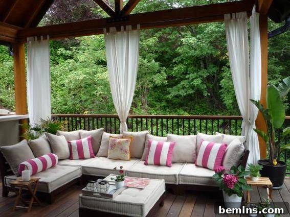 A stylish wooden corridor featuring a comfortable sofa, cushions, plants, trees, and elegant outdoor curtains.