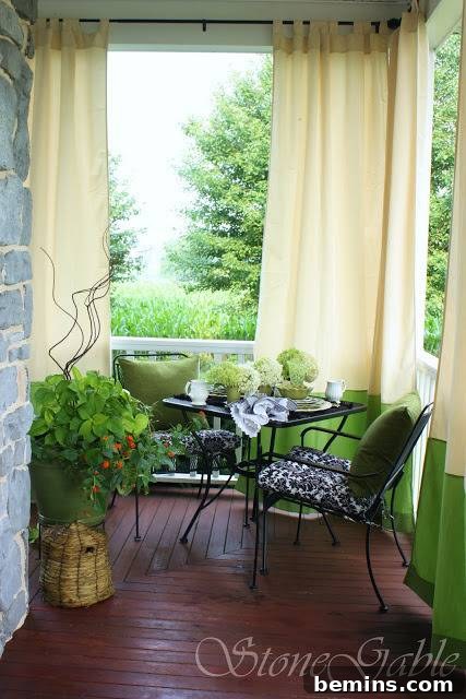 A beautifully designed patio with black tables and a curtained area, creating a private and stylish outdoor space.