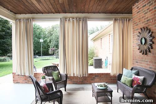 Black chairs sitting outside a brick building in a curtained-off area, creating a private and cozy outdoor space.