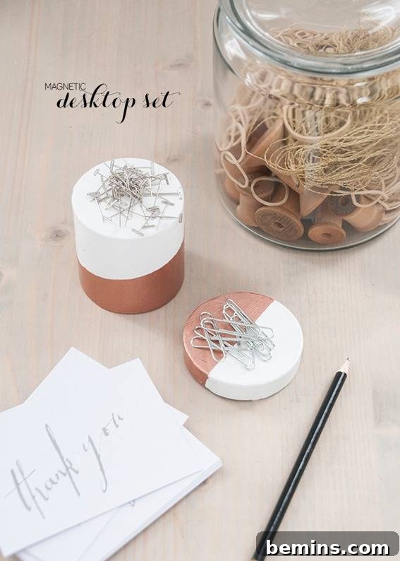 One box of magnetic clips and pins lying near some papers, a pencil and a jar.
