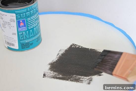 Black enamel being painted on a white surface.