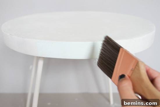 Someone painting a small white endtable.