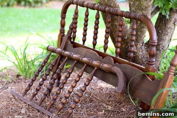 Broken down bed frame leaning against a tree outside.