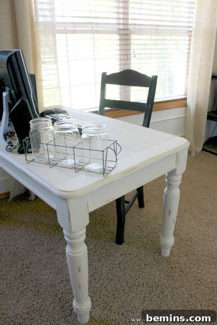 A white table has a green chair under it.