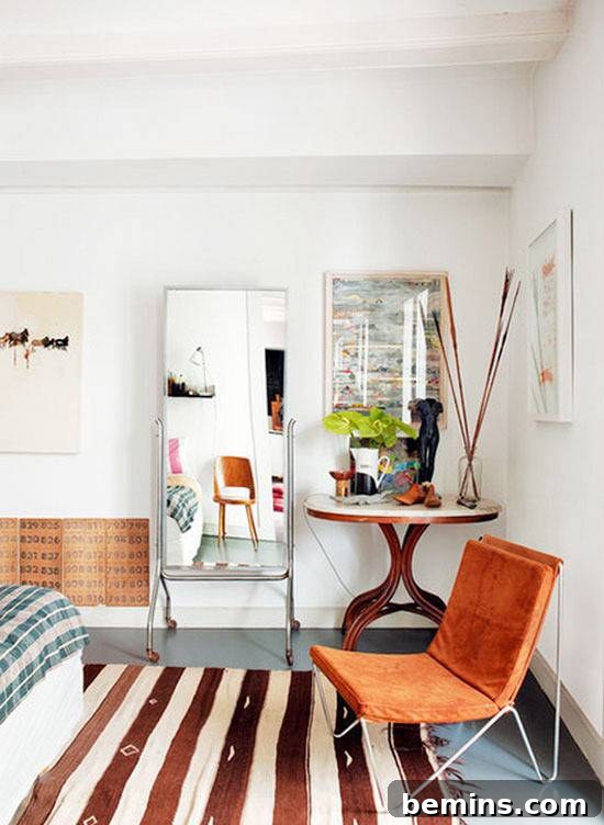 A stylish bedroom featuring a comfortable bed, an orange accent chair, and a decorative mirror.