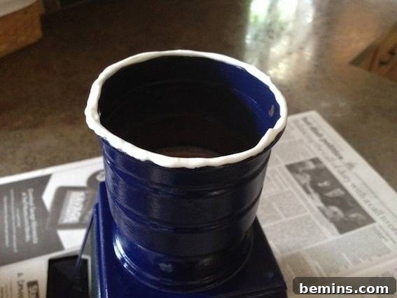 A blue cup with a white rim on a newspaper, used as a temporary support during the gluing process.