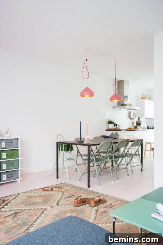 A stylish metal dining table with folding chairs illuminated by two striking orange pendant lights.