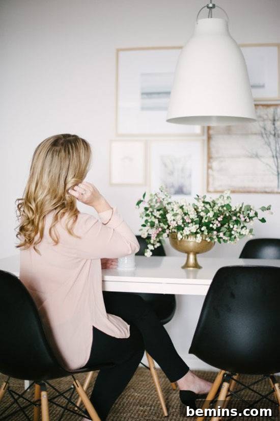 A stylish individual seated at a white table with a floral arrangement, exuding an air of elegance and sophistication.