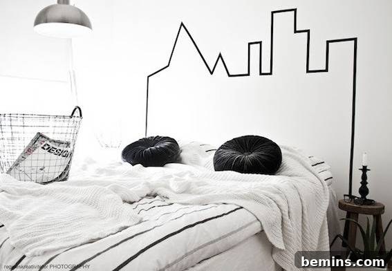 A bed has two round black pillows and a city design on the wall behind it.
