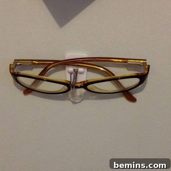 A pair of brown eyeglasses sitting on an eyeglasses stand.