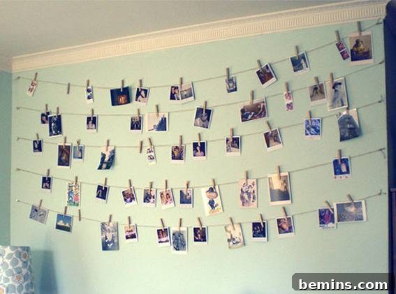 A wall has a bunch of photos hanging from strings on it.