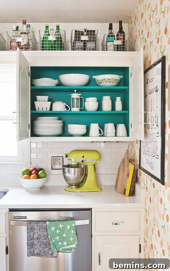 A kitchen has a white desk and teal cupboard.